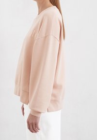 Felpa rosa chiaro con vestibilità comoda, caratterizzata da maniche lunghe, scollo rotondo e ricamo discreto del logo sul petto.