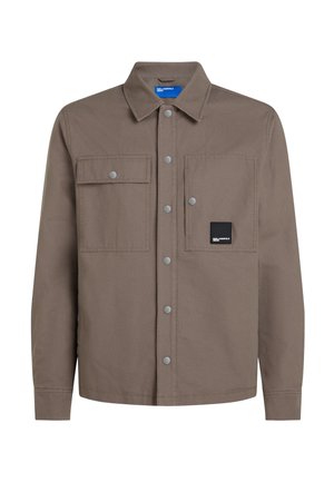 Veste-chemise marron taupe à boutons avec deux poches avant à rabat, col décontracté et une poche avec un petit patch de marque noir.