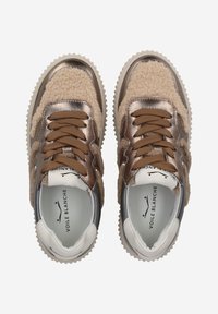 Baskets avec une finition métallique dorée et un matériau moelleux beige. Lacets marron et semelle blanche texturée. L'intérieur présente un branding.