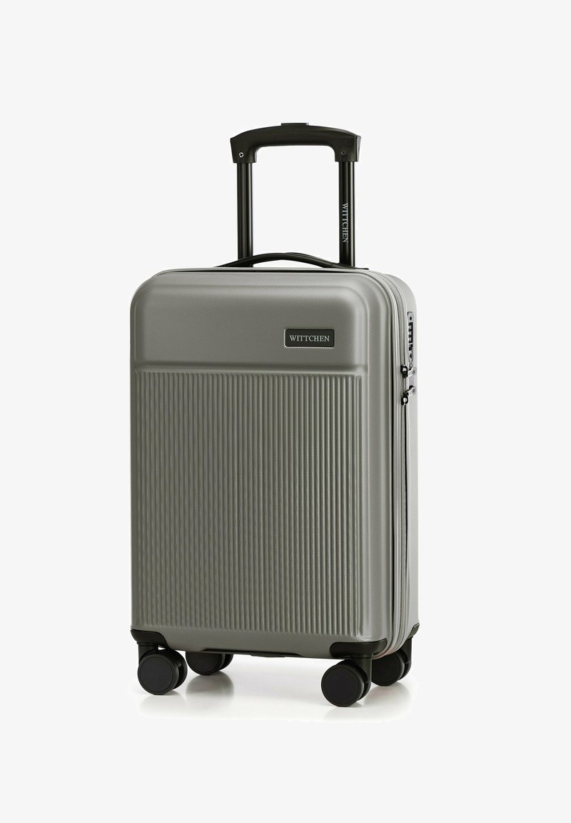 Šedý tvrdý kufr s vertikální zdrsněnou texturou, teleskopickou rukojetí a čtyřmi černými kolečky. Logo značky viditelné na přední straně.
