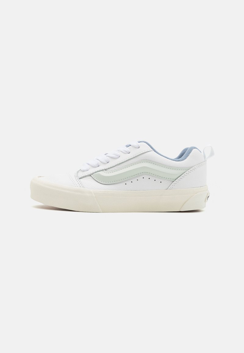 White sneaker with light blue accents, featuring a smooth leather exterior, lace-up closure, perforated detailing, and a rubber sole.