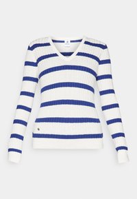 V-ringad tröja i vitt och blå ränder, ribbad textur, långa ärmar, figurnära design, liten logotypdetalj på sidan.