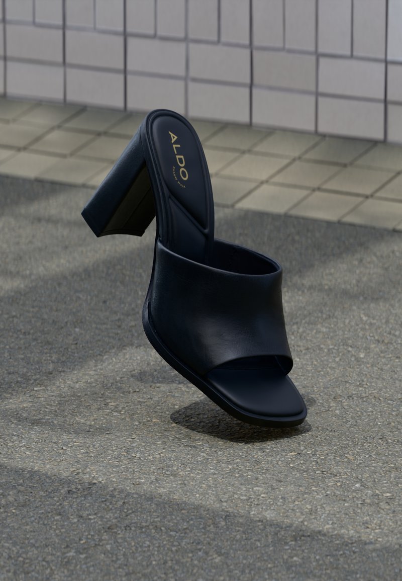 Fekete magas sarkú papucs vastag pánttal, négyzet alakú orral és ALDO márkajelzéssel a párnázott talpbetéten, struktúrált járdafelület háttér előtt.