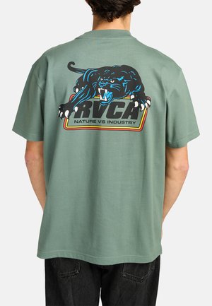Zielona bawełniana koszulka z krótkim rękawem, ozdobiona kolorową grafiką pantery oraz napisem "RVCA NATURE VS INDUSTRY" na plecach. Luźny krój.
