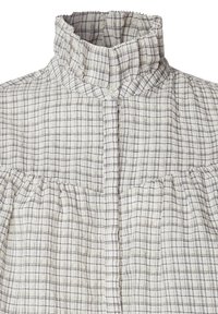 Blouse à col montant avec motif à carreaux blancs et gris et détail de tissu froncé sous le yoke avec fermeture à bouton au col.