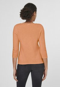 Oranje, lichtgewicht trui met driekwartmouwen, een ronde halslijn en een zachte textuur, gecombineerd met donker jeans.