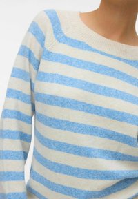 Pull rayé en crème et bleu clair, avec une texture douce, un col large et des manches longues. Les rayures sont horizontales et uniformément espacées.