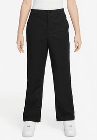 Μαύρο παντελόνι με ίσια γραμμή, κατασκευασμένο από απαλό ύφασμα· διαθέτει κούμπωμα με κουμπί μπροστά και θηλιές για ζώνη. Φοριέται με λευκά αθλητικά παπούτσια.