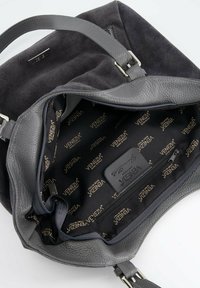 Grijze leren en suède handtas met ritssluiting. Het interieur heeft een gevoerd met logo stof en een extra ritszak voor organisatie.