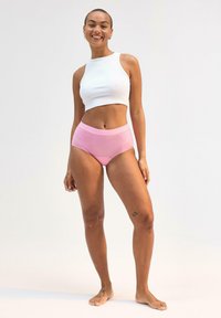 Vitt ribbat kort topp och rosa högmidjade underkläder. Tyget verkar mjukt med en slät yta, designat för komfort och lätthet i rörelse.