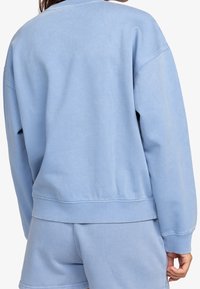 Felpa azzurro chiaro in misto cotone, con scollatura rotonda, spalle abbassate, polsini a costine e vestibilità rilassata.