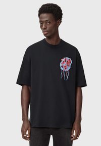 Must värvitud lühikeste varrukatega T-särk, millel on sinine ja punane tilkuv graafika disain vasakul rinnal. Puuvillane materjal, mugav lõige.