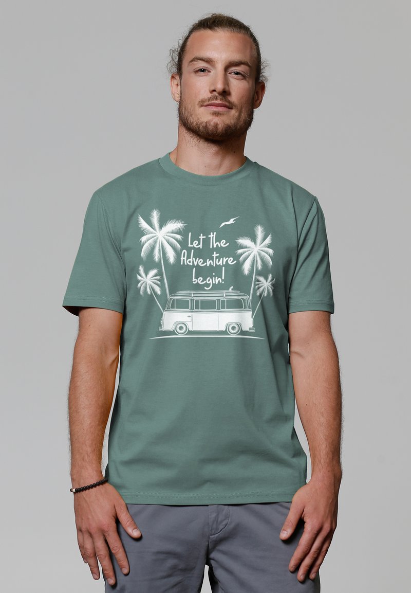 Korte mouwen teal t-shirt met een witte afbeelding van een busje met palmbomen en de tekst "Laat het avontuur beginnen!" in een informele lettertype.