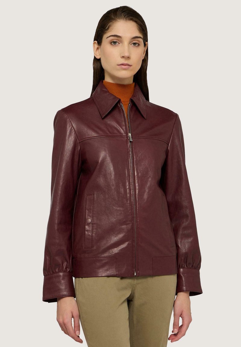 Burgundy läderjacka med en strukturerad design, spetsig krage och dragkedja fram. Har två framfickor och breda manschetter.