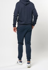 Navy-Hoodie mit Kängurutasche, Bündchenärmeln und passenden Jogginghosen. Das Outfit hat eine lockere Passform und besteht aus einem weichen, dehnbaren Stoff.