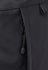 Black zippered pouch made of smooth, matte material, featuring a textured zipper pull and neat stitching along the edges.
