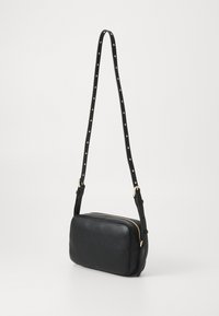 Borsa a tracolla nera in pelle con una forma rettangolare elegante, zip dorata e tracolla borchiata per un tocco in più.