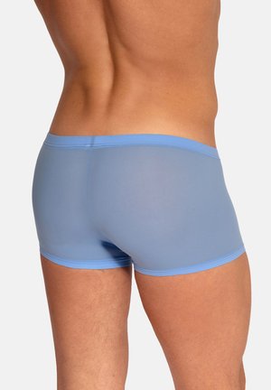 Männlicher Oberkörper und obere Beine in hellblauen, eng anliegenden Boxershorts, von hinten vor neutralem Hintergrund gezeigt.
