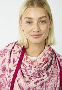 Écharpe en textile de couleur rose clair avec des motifs floraux rouges et violets ; texture douce avec une bordure unie rose foncé ; drapée élégamment autour du cou.