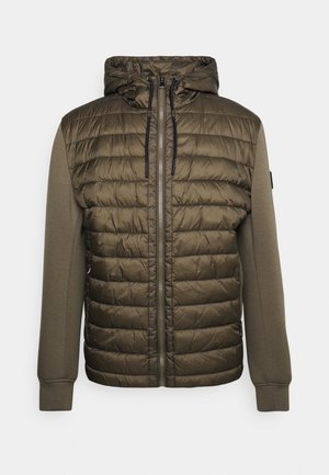 Veste à capuche vert olive avec devant matelassé, manches en tissu lisse, fermeture à glissière et cordons noirs sur la capuche.