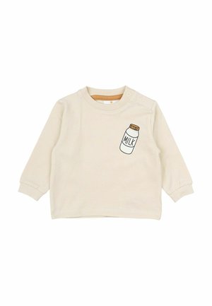 Cremfarbendes langärmliges Hemd aus Baumwolle, das auf der Vorderseite mit einem Grafikdesign einer Milchflasche und Druckknöpfen an der Schulter versehen ist.
