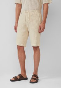 Beige mesh shorts met een trekkoord taille en een relaxte pasvorm. Gepaard met donkerbruine sandalen met dubbele banden en een vlakke zool.