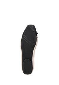 Suela de zapato con un fondo de goma negra que presenta patrones de agarre texturizados y un borde color crema, diseñada para ofrecer tracción y durabilidad.