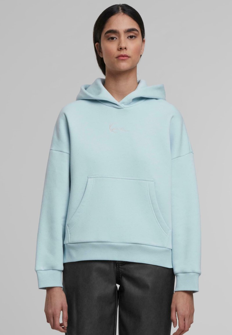 Helles blaues Hoodie aus weichem Stoff, mit einer Kängurutasche, gerippten Bündchen und einem kleinen, dezenten Logo auf der Vorderseite.