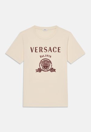 T-shirt beige à manches courtes avec col rond, comprenant "VERSACE Est. 1978" et le logo tête de Méduse en marron sur le devant.