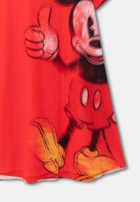 Czerwona sukienka z krótkim rękawem, uszyta z gładkiego materiału, z graficznym wzorem przedstawiającym postać z kreskówki z gestem kciuka w górę i żółtymi butami.