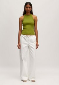 Groen geribbeld tanktop met een hoge halslijn, gecombineerd met losse witte broeken met een elastische tailleband en trekkoorddetail.