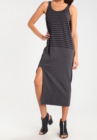 Mörkgrå tankklänning med horisontella ränder, knä-hög slits, tillverkad av mjukt tyg, i kombination med svarta ankelskor med dragkedjor.