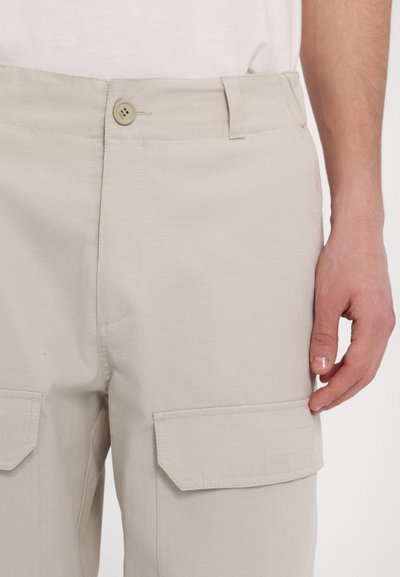 Pantaloni cargo bej deschis, confecționați dintr-un material texturat, cu închidere prin buton, două buzunare cargo și un design frontal plat.