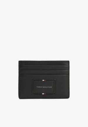 Porte-cartes noir Tommy Hilfiger avec trois emplacements pour cartes et écusson logo avec des rayures rouges, blanches et bleu marine.