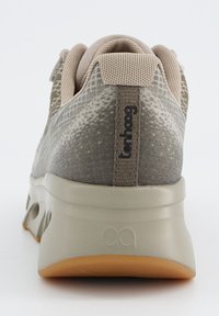 Graue Sportschuh mit einem strukturierten Obermaterial aus Stoff, leicht beige Akzenten, gepolstertem Kragen und einer flexiblen Gummisohle mit sichtbaren Luftkanälen.