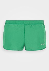 Calções de banho verdes feitos de um tecido leve e brilhante. Apresentam um cós elástico e um detalhe em texto branco no lado inferior direito.
