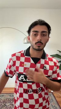 Rød- og hvitrutete fotballtrøye med svarte detaljer, krage og to stjerner over venstre bryst. Har logoen "Replik."