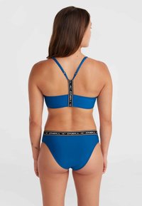 Set bikini blu con un design semplice, caratterizzato da un top con schiena a corsetto e uno slip alto, entrambi con bande loghi nere a contrasto.