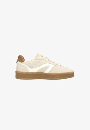 Beige en witte lage sneaker met rubberen zool, suède hielstuk en golvend zijdesign, gezien vanaf de buitenkant.