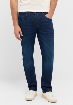 Heren donkere denim jeans met een rechte pasvorm, vijf zakken en een vervaagde afwerking. Gekocht met witte sneakers en een lichtgekleurde shirt.