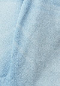 Tissu en denim bleu clair avec une texture fine de tissage diagonal et un pli subtil près du centre.