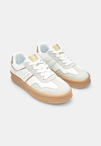 White and grey sneakers with a textured suede overlay, featuring a contrasting gum sole, white laces, and gold accents on the tongue.