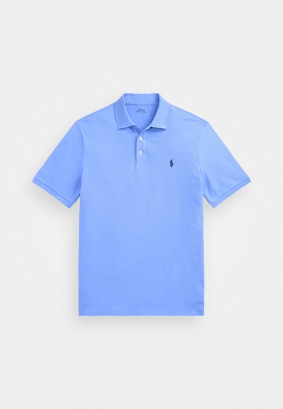 Svetlo modra polo majica iz bombaža, ki ima tri gumbe na zapenjanju in majhen vezen logotip na levem prsnem delu. Kratke rokave.