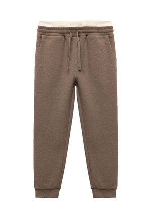 Braune, strukturierte Jogginghosen mit elastischem Bund und Kordelzug, versehen mit Cremetönen. Die Bündchen sind eng an den Knöcheln.