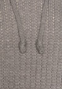 Graues gestricktes Material mit einem strukturierten Muster und auffälligen verdrehten Knoten. Die Oberfläche zeigt eine dezente, weiche Textur und sichtbare Stichdetails.