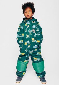 Mono impermeable verde con patrones de vehículos de construcción, con capucha forrada de forro polar y secciones verdes contrastantes en las piernas.