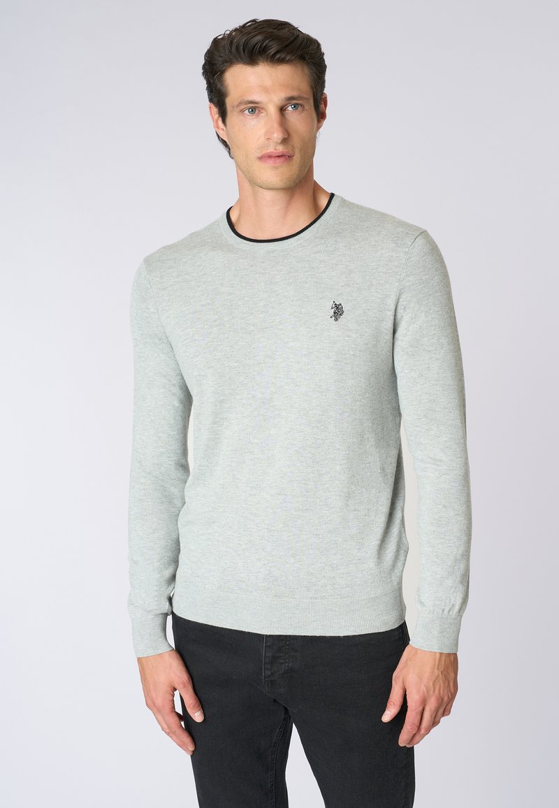 Maglioncino grigio chiaro in materiale lavorato a maglia, con maniche lunghe, scollatura a girocollo con profilo nero a contrasto e un piccolo logo sul petto.