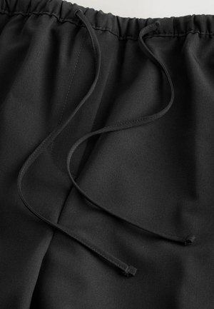 Schwarze Sportshorts mit einem elastischen Bund und inneren Kordelzügen. Glattes, leichtes Material mit subtiler glänzender Textur.