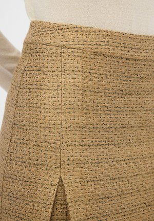 Teksturowana beżowa spódnica z delikatnym, tkanym wzorem i małym rozcięciem, z złotymi akcentami i dopasowanym krojem.