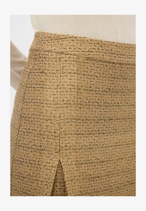 Teksturowana beżowa spódnica z delikatnym, tkanym wzorem i małym rozcięciem, z złotymi akcentami i dopasowanym krojem.